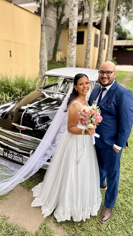 Frente do Chevrolet 1951 com placa e capô cromado, noiva com véu e noivo de terno azul ao lado