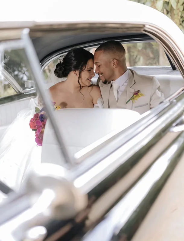 Casal sentado no banco branco do Chevrolet 1951, visto pela janela com acabamentos cromados